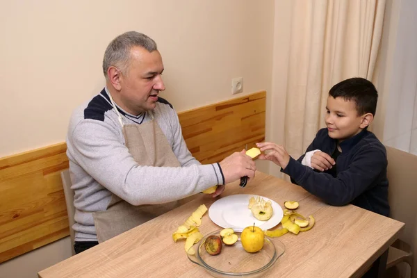 İnsan elmayı masadaki çocuğa uzatır, sıcak bir ilgi ve yakınlık anı yaratır..