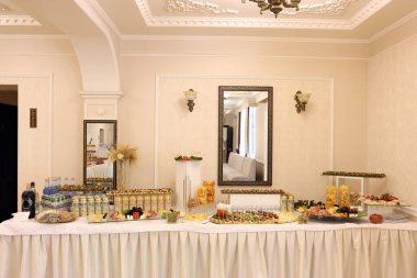 Lvivske birası, kanepeler ve aperatiflerle dolu geniş bir ziyafet masası; şenlikli bir misafir resepsiyonu hazırlığı. Salonda..