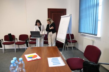 Ofisteki iki kadın sunuma hazırlanırken evrakları okuyup laptopa bakıyorlar..