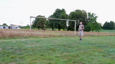 Eski futbol kalelerinin yakınındaki bir sahada badminton oynayan iki kişi, açık havada eğlencenin tadını çıkarıyorlar..