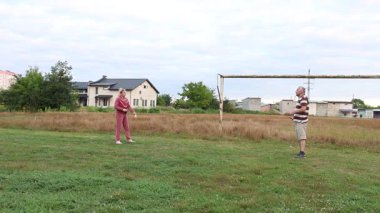 Spor giysili bir kadın partneriyle badminton maçı sırasında mekik aletine raketle vuruyor..