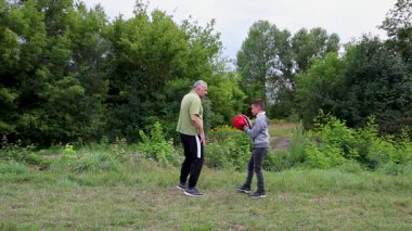 Koç ve çocuk doğada boks, pedlerin üzerinde pratik yapıyor..