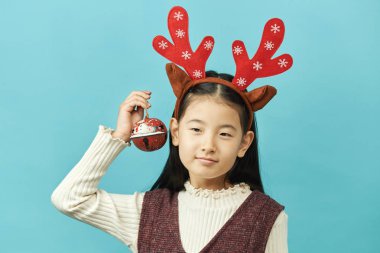 Bir Noel kavramı headdress ile Asyalı kız çocuk, yakın çekim izole mavi arka plan şirin küçük Asyalı kız.