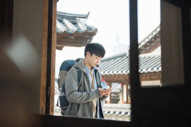 Kore geleneksel evde bir sırt çantasıyla yolculuk yapan bir genç erkek.