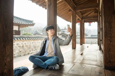 Kore geleneksel evde bir sırt çantasıyla yolculuk yapan bir genç erkek.