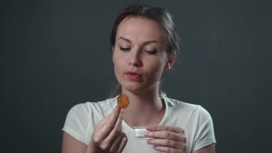 Genç kadın patates yiyor. İzole siyah. Portre.