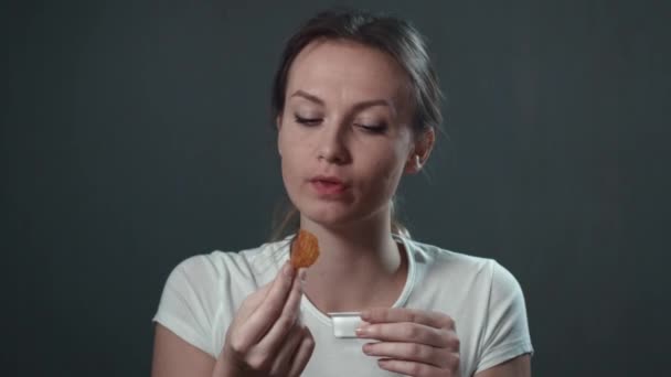 Mujer joven comiendo papas. Negro aislado. Retrato . — Vídeo de stock