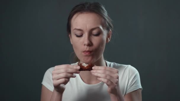 Mujer joven comiendo alitas de pollo. Negro aislado. Retrato . — Vídeos de Stock