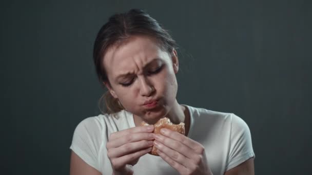 Closeup portrait of girl eating burger. Isolated black. Portrait. — Stock Video