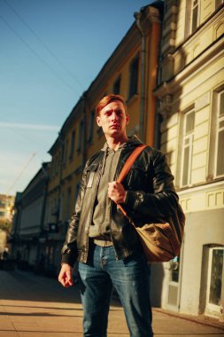 Yakışıklı, vahşi adam bir şehir sokak üzerinde duruyor ve gökyüzüne görünüyor.