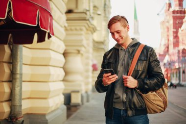 Acımasız adam şehirde standları ve smartphone gülümseyen kullanır