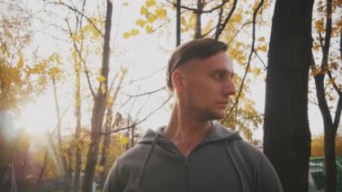 Acımasız genç adam parkta etrafına bakıyor.