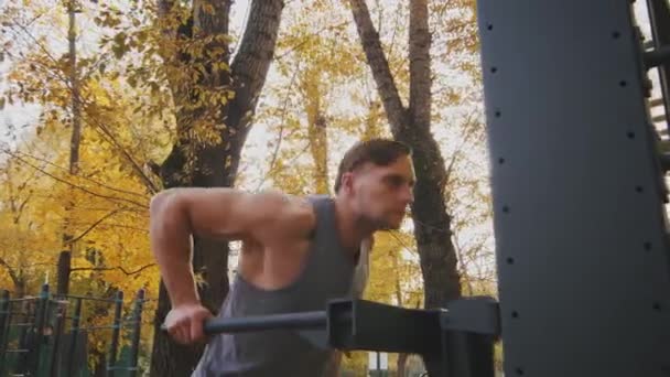 Joven atleta hace ejercicio en barras paralelas — Vídeo de stock