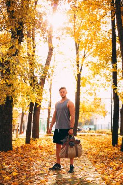 Yakışıklı bir erkek spor giyim Sonbahar bir parkta duruyor