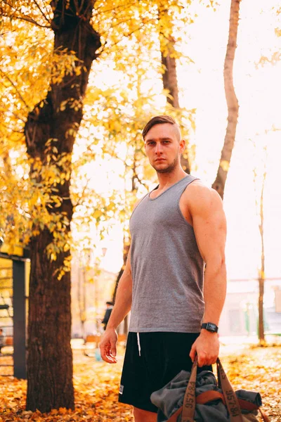 Ein gutaussehender Mann steht in Sportbekleidung im Herbstpark — Stockfoto