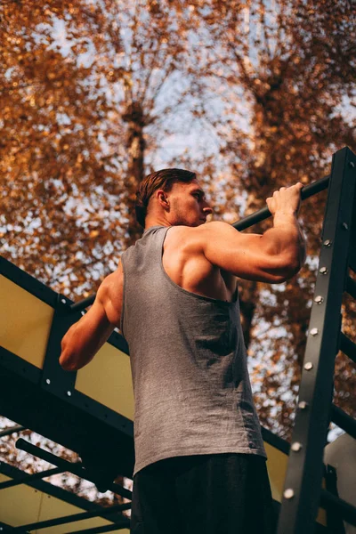 Giovane atleta maschio sexy fa pull-up nel parco — Foto Stock