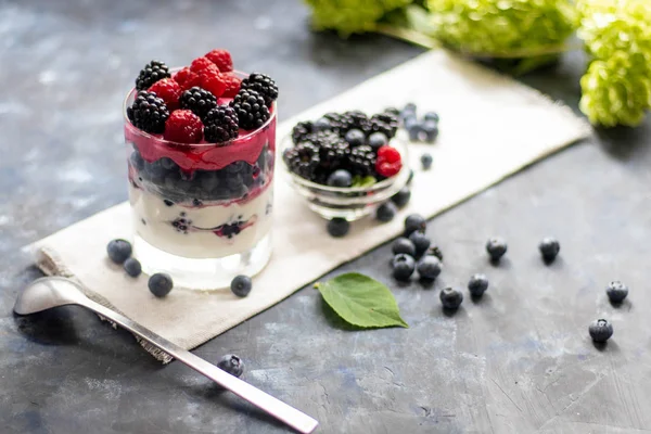 Sağlıklı beslenme Diyet tatlılar. Bardaklar süzme peynir kreması ile doludur, onları chia tohumu, ahududu, yaban mersini, böğürtlen. Arka plan çiçekleri için yakın.
