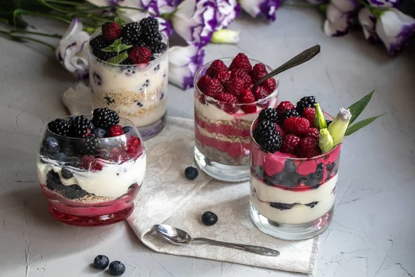 Sağlıklı beslenme Diyet tatlılar. Bardaklar süzme peynir kreması ile doludur, onları chia tohumu, ahududu, yaban mersini, böğürtlen. Arka plan çiçekleri için yakın.