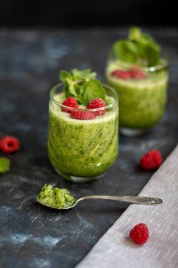 Diyet içeceği, smoothie. Yeşil renk. Vücut temizliği. Diyet. Salatalık, elma, limon, zencefil, avokado. Bir bardak ahududu da. Kaşıkta yemek. Sağlıklı beslenme. Hafif kahvaltı. 