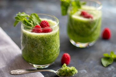 Diyet içeceği, smoothie. Yeşil renk. Vücut temizliği. Diyet. Salatalık, elma, limon, zencefil, avokado. Bir bardak ahududu da. Kaşıkta yemek. Sağlıklı beslenme. Hafif kahvaltı. 