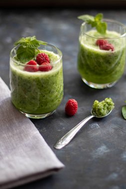 Diyet içeceği, smoothie. Yeşil renk. Vücut temizliği. Diyet. Salatalık, elma, limon, zencefil, avokado. Bir bardak ahududu da. Kaşıkta yemek. Sağlıklı beslenme. Hafif kahvaltı. 