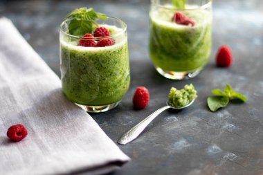 Diyet içeceği, smoothie. Yeşil renk. Vücut temizliği. Diyet. Salatalık, elma, limon, zencefil, avokado. Bir bardak ahududu da. Kaşıkta yemek. Sağlıklı beslenme. Hafif kahvaltı. 