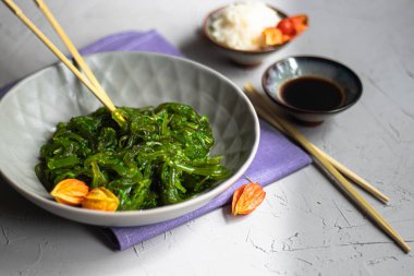 Yosun Salatası. Diyet ve tiroid bezi için çok yararlı. Bitkisel yağ ile giyinmiş, susam serpilir. Ahşap çubukların yanında. 