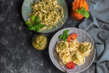 Tagliatelle makarna pesto ile aldente pişmiş. Soslu, physalis, zeytinli kaseye yakın. Eriştefelik yeşil sprigs ile dekore edilmiştir. Sağlıklı yaşam deneyimi. Doğru beslenme. Vejetaryen yemek. 