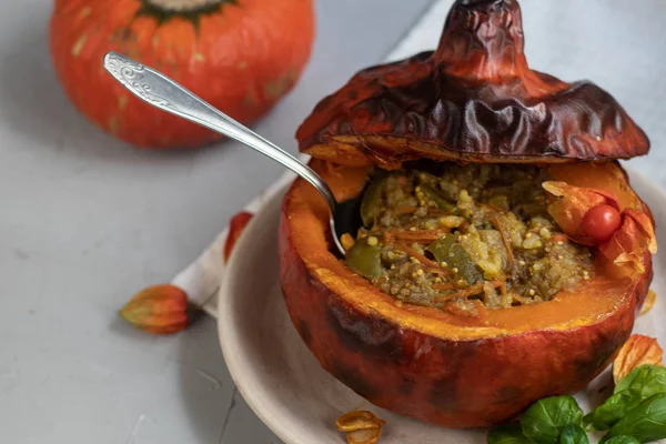 Baked pumpkin stuffed with vegetable stew with rice. Nearby are the berries of physalis, and in the background is a fresh orange tavern. healthy lifestyle. Proper nutrition. Diet.