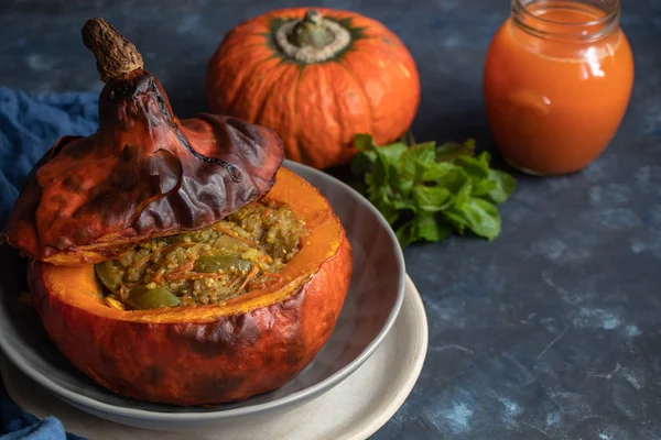 Baked pumpkin stuffed with vegetable stew with rice. Nearby are the berries of physalis, and in the background is a fresh orange tavern. healthy lifestyle. Proper nutrition. Diet.