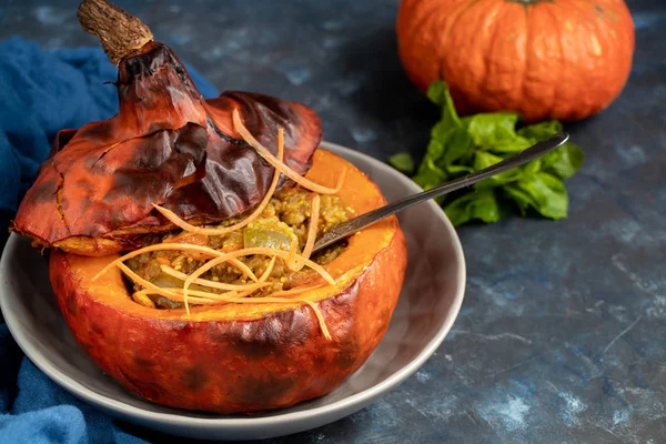 Baked pumpkin stuffed with vegetable stew with rice. Nearby are the berries of physalis, and in the background is a fresh orange tavern. healthy lifestyle. Proper nutrition. Diet.