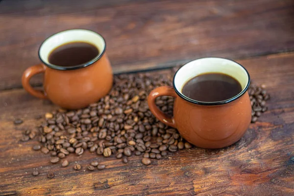 茶色のカップにコーヒー 熱くて爽快な飲み物 コーヒー豆が近くに点在しています 背景の自家製カップケーキで — ストック写真