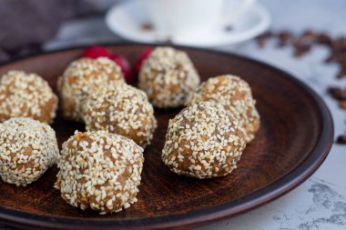 Kahverengi kil plaka üzerinde Hint Lada topları vardır. Onlar susam serpilir. Her şey granit dekore edilmiş gri bir arka plan üzerinde yer almaktadır. 
