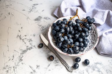 Büyük, siyah, şaraplı üzümler. Maya adı verilen beyaz bir kaplama ile kaplıdır. Onların yardımıyla şarap elde edilir. Meyvelerüzerinde su damlaları, dekorasyon için gri bir kumaş yanında. 