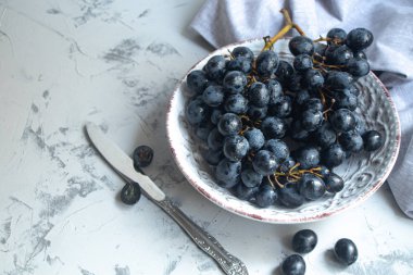 Büyük, siyah, şaraplı üzümler. Maya adı verilen beyaz bir kaplama ile kaplıdır. Onların yardımıyla şarap elde edilir. Meyvelerüzerinde su damlaları, dekorasyon için gri bir kumaş yanında. 