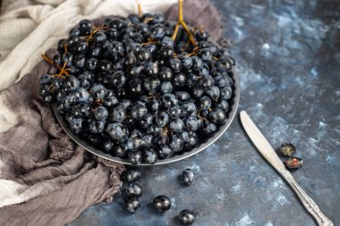 Büyük, siyah, şaraplı üzümler. Maya adı verilen beyaz bir kaplama ile kaplıdır. Onların yardımıyla şarap elde edilir. Meyvelerüzerinde su damlaları, dekorasyon için gri bir kumaş yanında. 