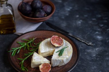 Olgun, güzel, mor incirler. Tatlı ve sulu. Akdeniz meyvesi çok sağlıklıdır. Tabakta Brie peyniri var. Karanlık bir telif uzayı arka planında boş bir alan var. Vejetaryenler için yiyecek..