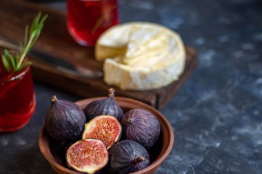 Olgun, güzel, mor incirler. Tatlı ve sulu. Akdeniz meyvesi çok sağlıklıdır. Tabakta Brie peyniri var. Karanlık bir telif uzayı arka planında boş bir alan var. Vejetaryenler için yiyecek..