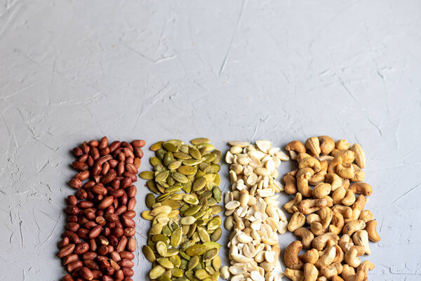Food for vegetarians and more. Nuts, seeds are very useful and rich in essential trace elements. Cashews, peanuts, pumpkin seeds are nutritious and delicious. Copy space. Grey background.