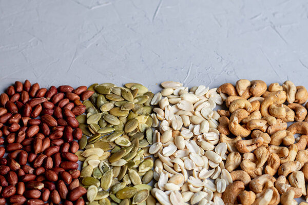 Food for vegetarians and more. Nuts, seeds are very useful and rich in essential trace elements. Cashews, peanuts, pumpkin seeds are nutritious and delicious. Copy space. Grey background.