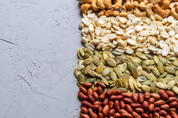 Food for vegetarians and more. Nuts, seeds are very useful and rich in essential trace elements. Cashews, peanuts, pumpkin seeds are nutritious and delicious. Copy space. Grey background.