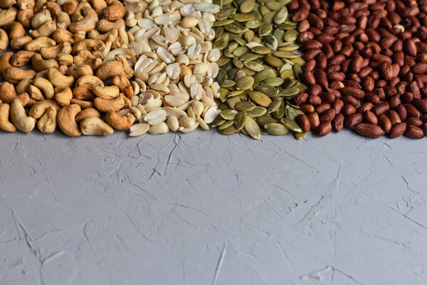 Food for vegetarians and more. Nuts, seeds are very useful and rich in essential trace elements. Cashews, peanuts, pumpkin seeds are nutritious and delicious. Copy space. Grey background.