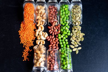 Vejetaryen yemekleri için çeşitli ürünler. Fasulye, bezelye, kabak tohumu, fındık, fıstık, mercimek. Protein ve sağlıklı elementler açısından zengin. Uzayı kopyala Koyu arkaplan.