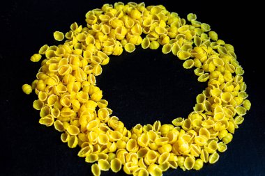 İtalyan makarnası koyu arkaplanda daire şeklinde dizilir. Ortası fotokopi alanı. Sağlıklı bir ürün yumurta içermez..