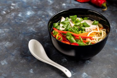 Buğday erişteli Asya çorbası, bir dilim et, kırmızı biber. Nane yaprağı, fesleğen, yeşil soğan tüyü ile süslenmiş. Havuç ve brokoli var. Sağlıklı, beslenme ürünü. Boşluğu kopyala. 