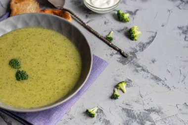 Yeşil brokoli kremalı çorba, chia tohumu, kırmızı soğan, yeşil biber, kiraz domatesleri ve kızarmış ekmekler açık gri, taş zemin üzerinde. Sağlıklı beslenme konsepti. Yukarıdan bak. Boşluğu kopyala.