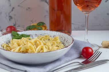 İtalyan makarnası, avokadolu spagetti, ıspanak, fesleğen, krem, peynir. Vejetaryen sebze makarnası. Erişteli ıspanak. Hafif bir arkaplanda. Arka planda bir bardak portakal şarabı var. Boşluğu kopyala. 