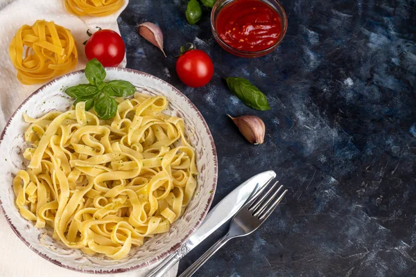 Italian pasta, spaghetti with avocado, spinach, basil, cream, cheese. Vegetarian vegetable pasta. Spinach with noodles. On a light background. Nearby are cherry tomatoes, olive oil. Copy space.