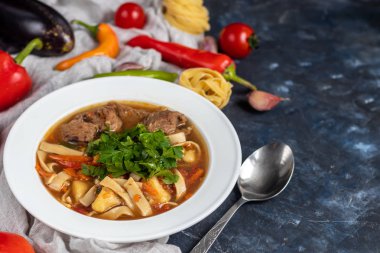 Doğu yemeği Lagman. Erişte, sığır eti, mavi, biber, domates. Yürekli yemek. Maydanoz ve kişniş ile süslenmiş. Karanlık bir arka planda. Boşluğu kopyala.