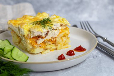 Tavuk göğsü, havuç ve soğanlı patates güveci. Peynirle kaplanmış. Taze sebzelerle süslenmiş. Ama gri bir arkaplan. Boşluğu kopyala.